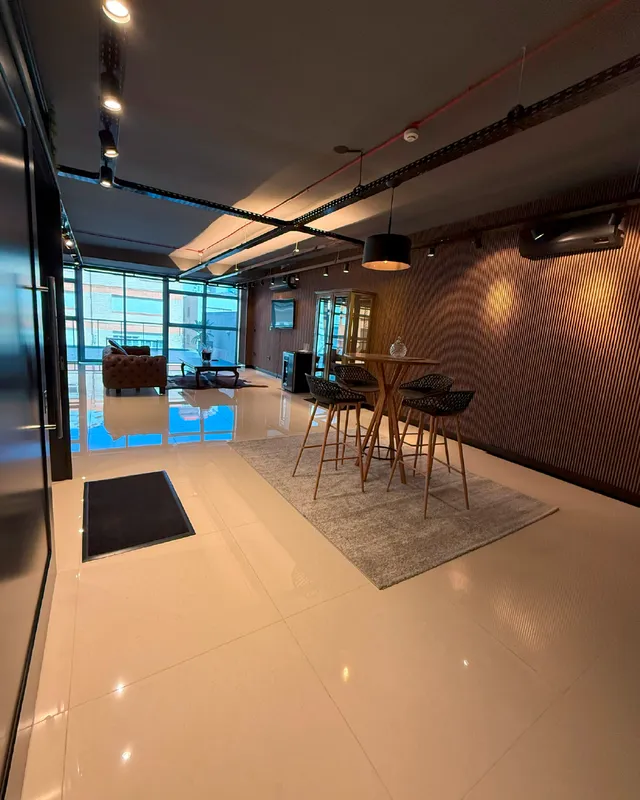 Sala de estar e jantar com piso claro e parede de madeira em um apartamento.
