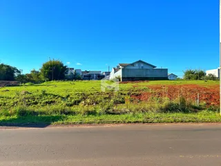 Vista externa de uma propriedade com campo gramado e um edifício ao fundo.