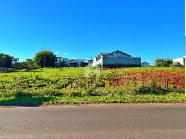 Vista externa de uma propriedade com campo gramado e um edifício ao fundo.