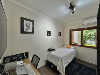 Quarto com cama e janela de madeira em imóvel no Brasil.