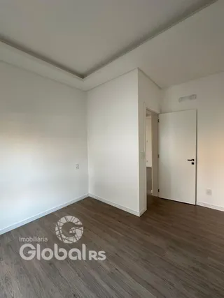 Foto de um cômodo interno com piso de madeira clara e paredes brancas.