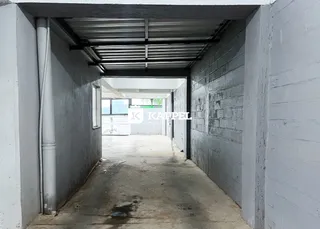 Corredor interno de um imóvel com piso de concreto e teto metálico.