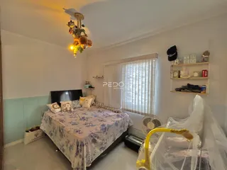 Quarto com cama e janela em ambiente claro.