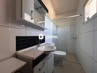 Banheiro com revestimento de azulejos brancos e bancada de apoio.