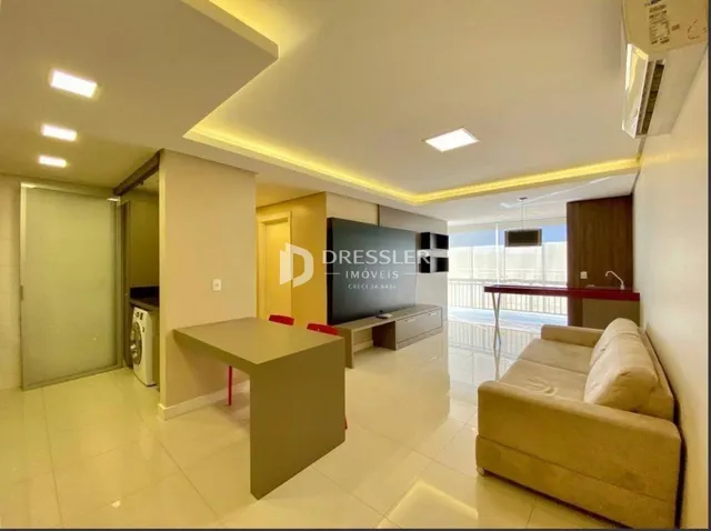 Sala de estar clara com sofá de cor bege e piso de cerâmica.