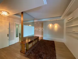 Sala de estar com piso de madeira e espelho refletindo o ambiente.