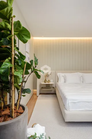 Foto de um quarto com cama e plantas em um ambiente claro.