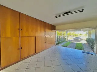Interior de uma sala com armários de madeira e piso de cerâmica que se abre para o exterior.