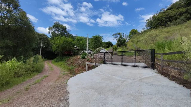 Vista da entrada da propriedade em uma área verde com estrada de terra.