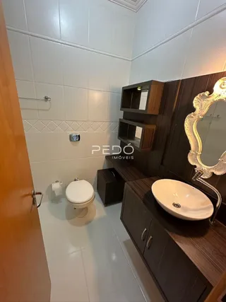 Foto de um banheiro com piso de cerâmica e armário de madeira.