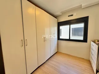 Quarto com armários brancos e piso de madeira clara.