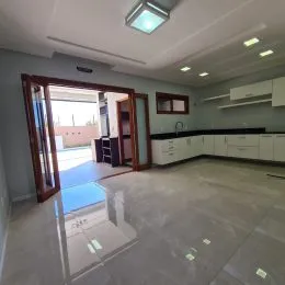Foto de uma cozinha ampla com armários brancos e piso claro.