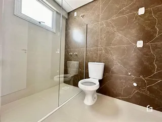 Foto de um banheiro com revestimento de mármore e box de vidro.