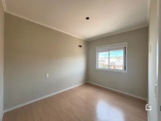 Ambiente interno de uma sala com piso de madeira clara e paredes neutras.