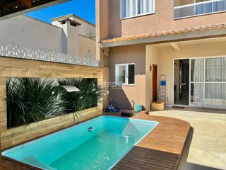 Vista externa de uma piscina com deck de madeira em uma residência.