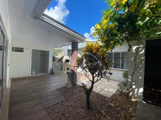 Área externa com deck de madeira e vegetação em uma residência.