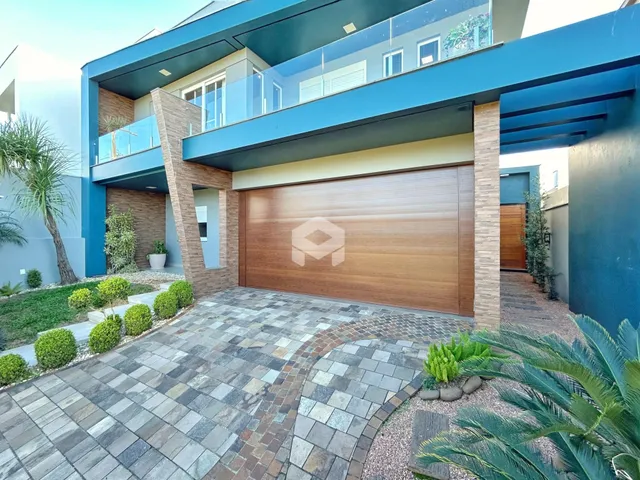 Fachada moderna de uma residência com garagem e área externa pavimentada.