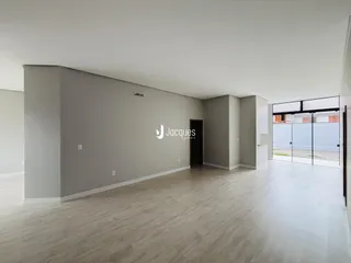 Ambiente interno de uma sala com piso de madeira clara e paredes cinzas.