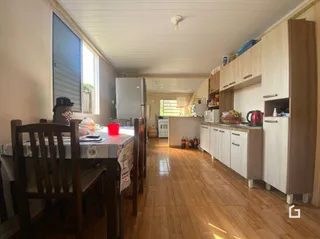 Interior de uma sala com piso de madeira e armários de cozinha.