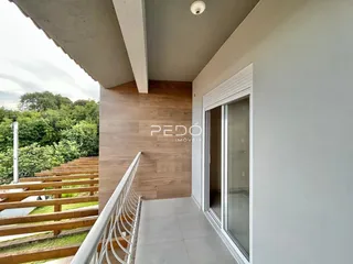 Vista da fachada de uma residência com grade de madeira e jardim.