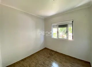 A sala apresenta paredes brancas e piso de madeira.