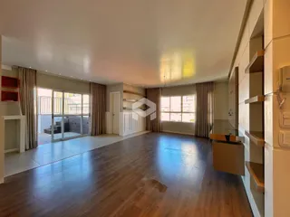 Sala de estar ampla com piso de madeira e portas de vidro que dão acesso ao exterior.