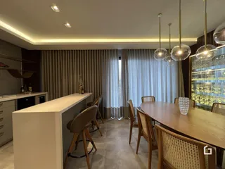 Vista de uma sala de jantar moderna com mesa de madeira e iluminação pendente.
