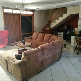 Sala de estar com sofá grande e piso de cerâmica em um imóvel.