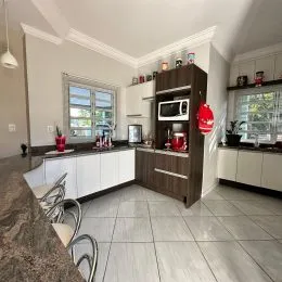 Foto interna de uma cozinha com armários brancos e piso claro.