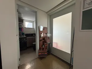 Hall de entrada com porta aberta mostrando uma cozinha e um corredor interno.