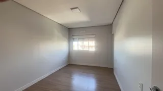 Vista interna de uma sala com piso de madeira clara e paredes brancas.