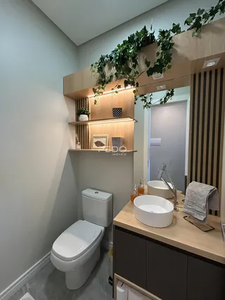 Banheiro moderno com bancada de madeira e revestimento de piso claro.