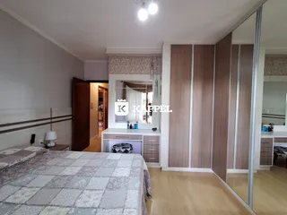 Quarto com cama grande e painel de madeira na sala de um imóvel.