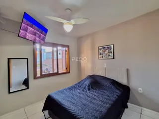 Quarto com cama e televisão montada na parede em um imóvel no Brasil.
