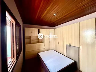 Quarto com cama e armários em madeira clara.