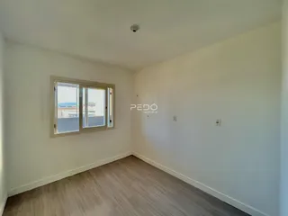Ambiente interno de uma sala com piso de madeira clara e janela.