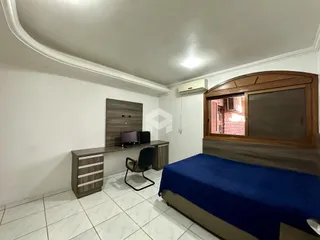 Quarto com cama e armário de madeira em um imóvel no Brasil.