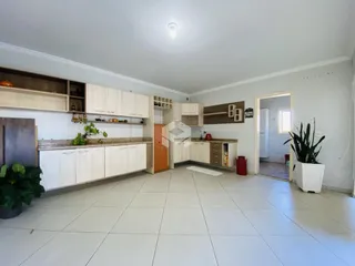 Interior de uma cozinha com armários brancos e piso claro.