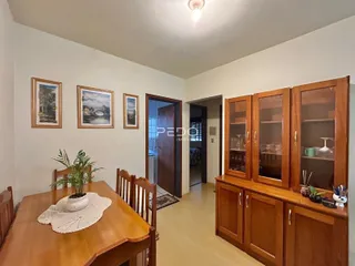 Interior de uma sala com paredes brancas e móveis de madeira.