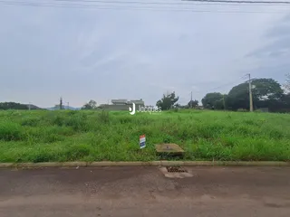 Vista externa de uma propriedade com área de grama e vegetação.