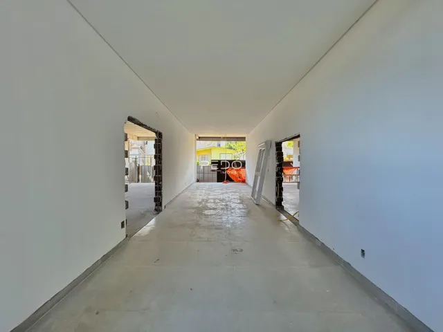 Corredor interno com paredes brancas e piso de concreto.