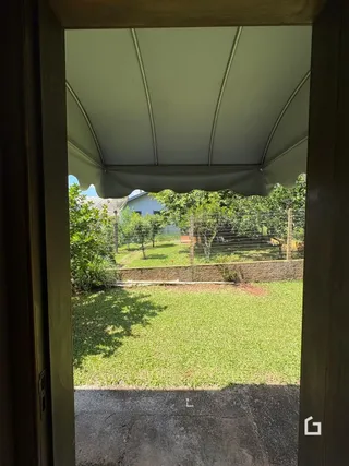 Vista do quintal gramado com cerca de madeira e estrutura de telhado.
