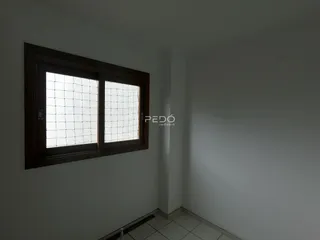 Vista interna de uma sala com janela e parede branca.