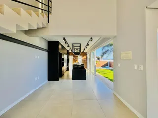 Corredor moderno com piso claro e acesso a uma área externa gramada.
