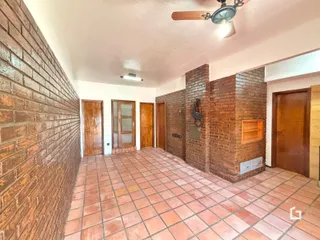 Hall de entrada com paredes de tijolo aparente e piso de cerâmica.