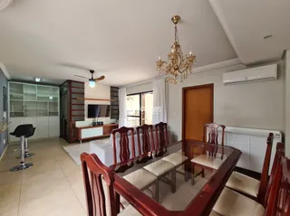 Sala de jantar com mesa e cadeiras de madeira em um imóvel no Brasil.