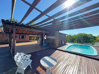 Vista de uma área externa com piscina e deck de madeira.