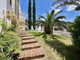 Vista da fachada de uma residência com jardim e escadaria de tijolos.