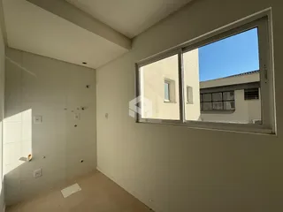 Vista interna de um ambiente com parede branca e janela grande.