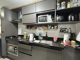 Cozinha moderna com armários escuros e bancadas pretas.